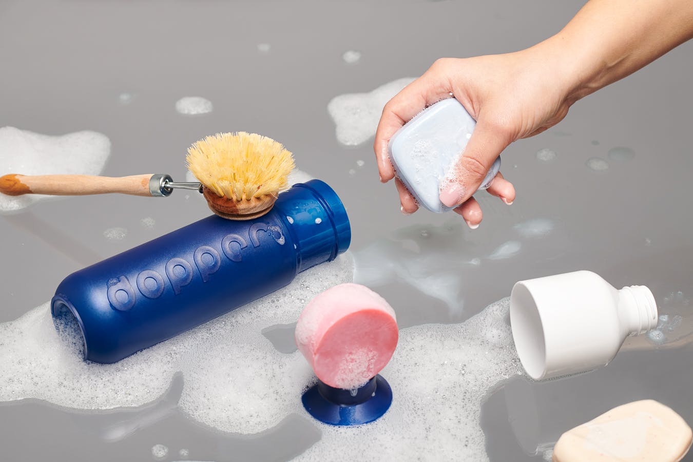 Cleaning supplies and foam cleaning a blue Dopper bottle