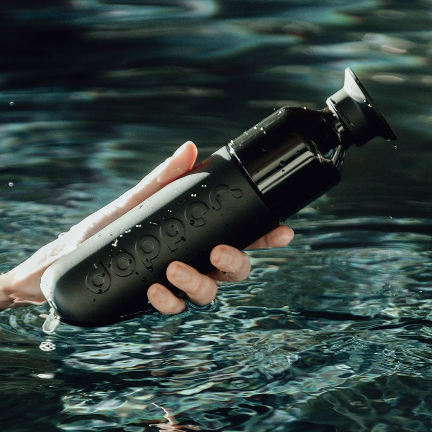 Person holding a black Dopper bottle from the water